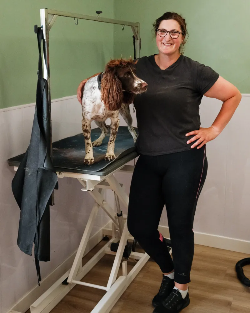 Emma standing beside the grooming table in the salon with a springer spaniel