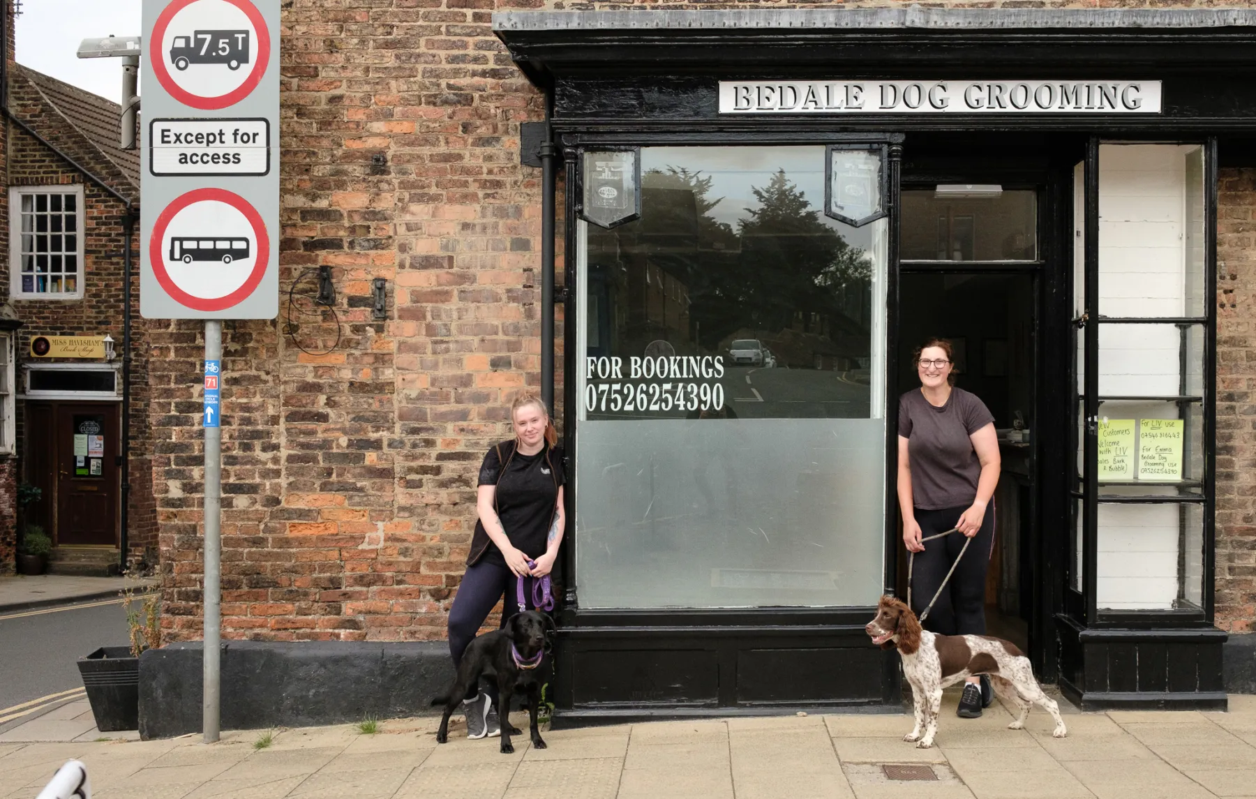 Emma and Liv outside Bedale Dog Grooming on Market Place with a black labrador and a springer spaniel